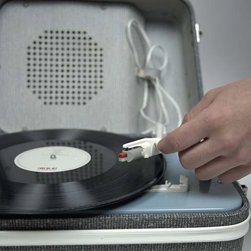 Photo d'une main en cours d'actionnement du tourne disque mettant le bras sur un vinyle