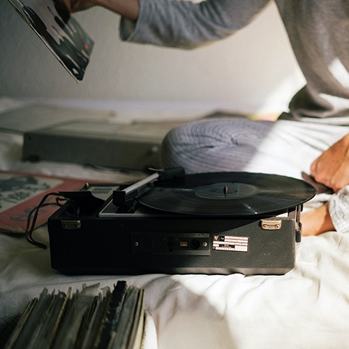 Photo d'illustration mettant en scène une personne sur un canapé et choisissant le prochain vinyle à mettre sur la platine